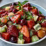 A vibrant bowl of strawberry lemonade fruit salad with juicy strawberries, blueberries, and pineapple in a zesty citrus dressing.