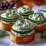 Delicate bite-sized Benedictine Cucumber Canapés featuring smooth Kentucky-style spread, garnished with dill and served on thin bread rounds.