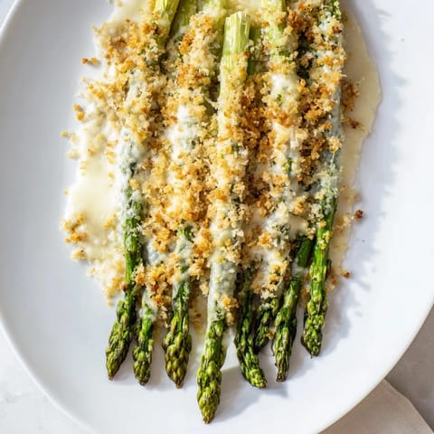 A close-up of a bubbling asparagus casserole with melted Gruyère cheese, ready to serve.