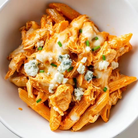 Creamy Buffalo Chicken Pasta with tender shredded chicken, blue cheese crumbles, and fresh chives on a rustic plate.