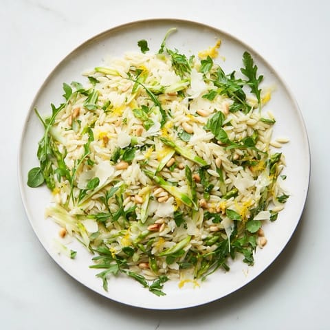 Spring orzo salad with crisp asparagus shavings, fresh herbs, and a bright lemon dressing in a white ceramic bowl.  
