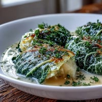 Golden Herby Cabbage in Parmesan Broth served in a rustic shallow bowl with extra herbs.