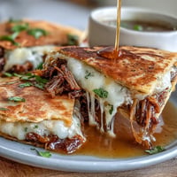 Crispy birria quesadillas stuffed with tender beef, served with a rich, spicy consommé for dipping on Cinco de Mayo.  
